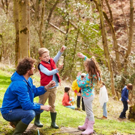 Børn udforsker naturen ved et vandhul