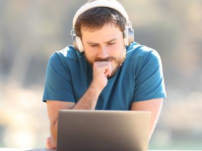 Mand læser og lytter på pc
